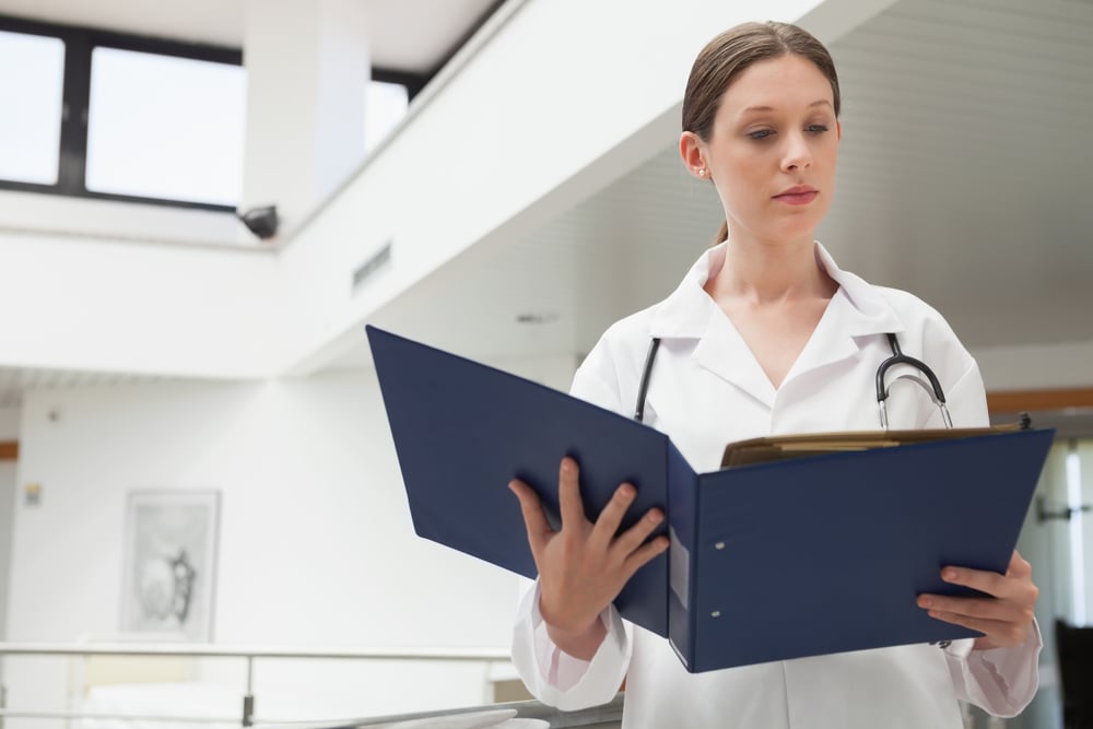 Female doctor reading  folder in hospital corridor